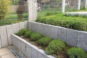 Stützmauer aus Granitblöcken mit bepflanztem Hochbeet dahinter