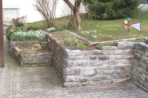 Natursteinmauer, die eine Rasenböschung abfängt